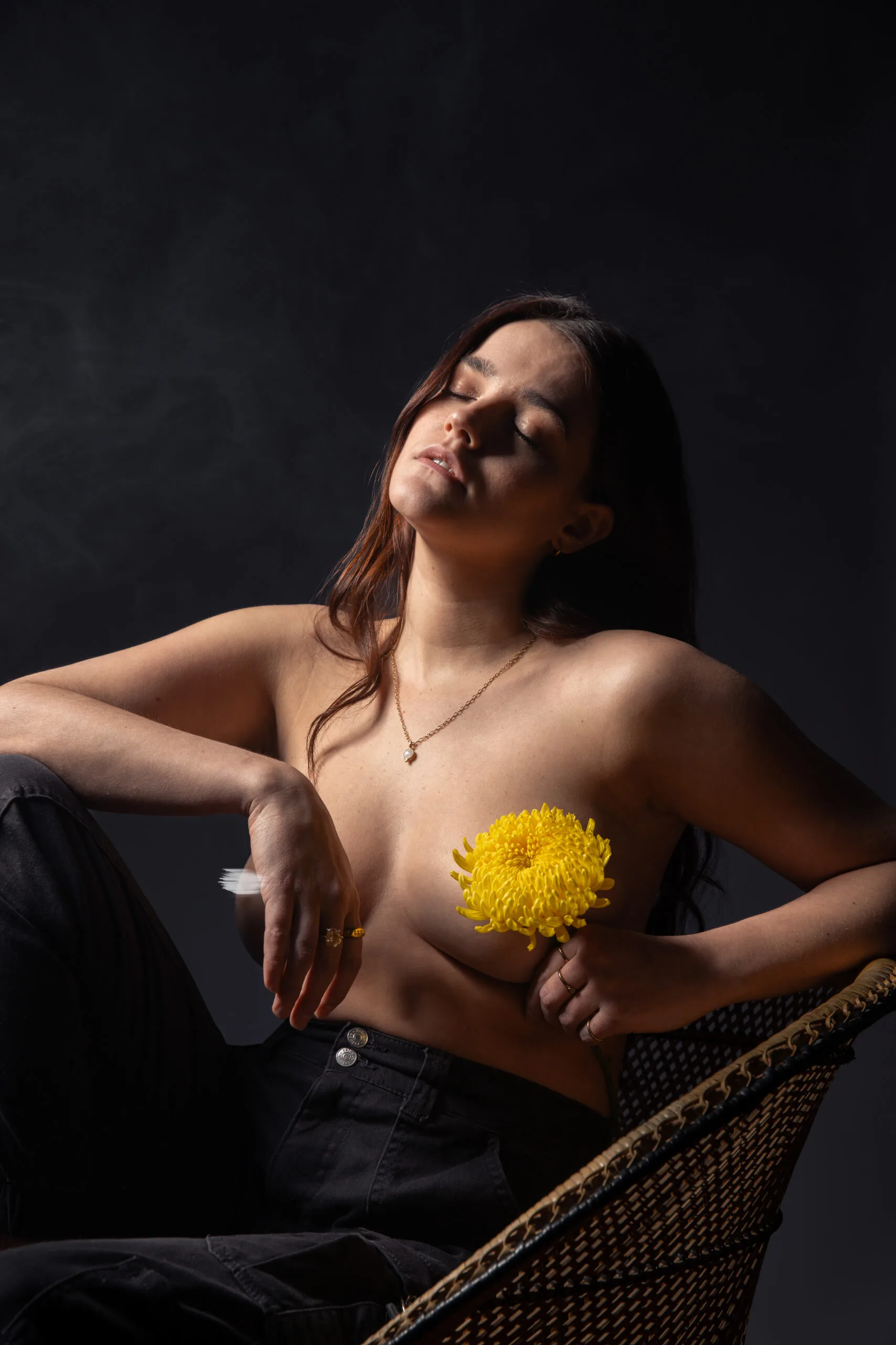 Photographie nue artistique – femme avec fleur jaune en main, lumière douce